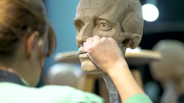 Beeldhouwer het creëren van beeldhouwkunst van mannen hoofd. Een vrouw die in de studio werkt. Neusconstructie anatomie — Stockvideo