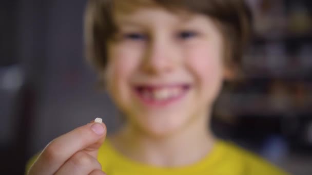 De jongens melktand viel uit. Een tevreden kind houdt een tand in zijn hand. Een gat in de gom is zichtbaar — Stockvideo