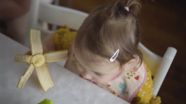 かわいい子供を食べる。赤ちゃんの女の子は自分で健康食品を食べる。ママと娘は — ストック動画