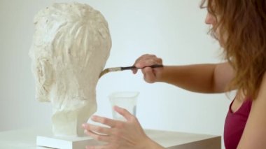 Heykeltıraş, insan kafasının alçıtaşı heykelini tamir ediyor. Stüdyoda çalışan kadın.