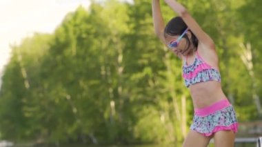 Tahta iskeleden göle atlayan dalgıç kıyafetli kız. Yaz günü eğleniyorum..