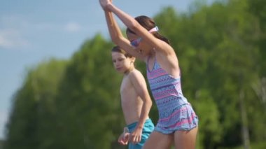 Dalgıç kıyafetli kız ve oğlan tahta iskeleden göle atlıyorlar. Yaz günü eğleniyorum..