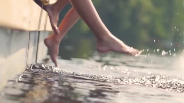 腿在水里。孩子们坐在码头上玩得很开心.泼水闭合 — 图库视频影像