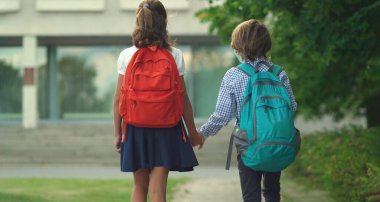 Çocuklar okula geri döner. Sırt çantalı sevimli gözbebekleri. Güvenlik maskeli kız ve erkek.