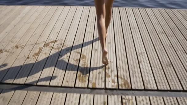女性は、湖に木製の桟橋からジャンプします。夏の日にお楽しみください。ドックから海に潜る若い女の子. — ストック動画