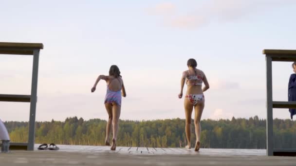 La familia feliz tiene vacaciones en el lago. Madre con hija saltar desde el muelle juntos. — Vídeos de Stock