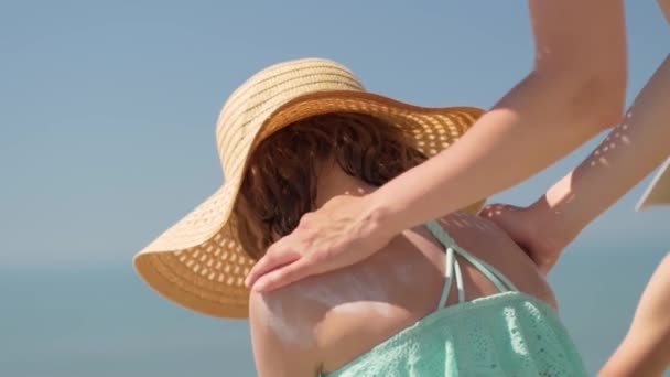 माँ अपनी बेटियों के कंधे पर सनब्लॉक क्रीम लगा रही है। बच्चों की त्वचा की सूरज की सुरक्षा . — स्टॉक वीडियो