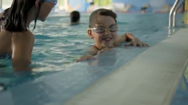 Happy children in swimming pool. Sports lifestyle concept. Boy and a girl in swimming lessons — Stock Video