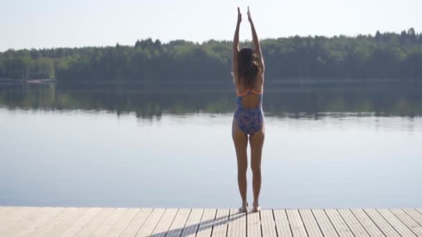 Frau springt von Holzsteg in den See Spaß haben an einem Sommertag. Junges Mädchen stürzt sich vom Dock ins Wasser. — Stockvideo