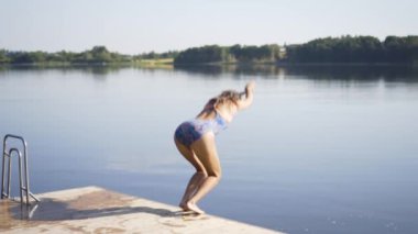 Ahşap iskeleden göle atlayan kadın. Yaz günü eğleniyorum. Rıhtımdan suya atlayan genç kız.