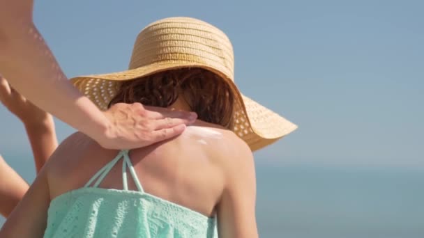 Matka nakłada krem przeciwsłoneczny na ramiona córek. Ochrona przeciwsłoneczna skóry dziecka. — Wideo stockowe