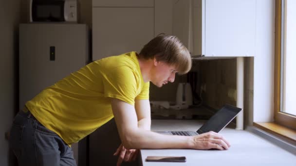 Un hombre utiliza un ordenador portátil para el trabajo distante en un proyecto. Trabajo desde el concepto del hogar — Vídeo de stock