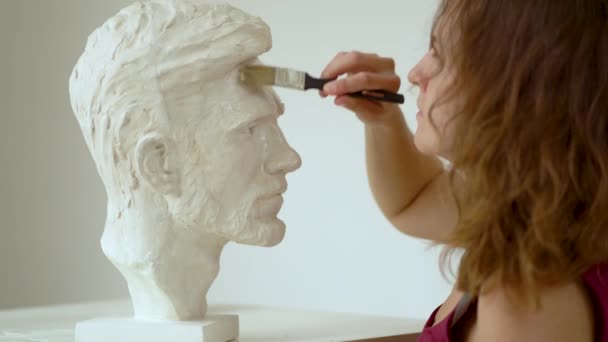 Sochař opravující sádrokartonovou sochu lidské hlavy. Žena pracující ve studiu — Stock video