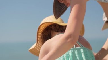 Anne, kızının omzuna güneş kremi sürüyor. Çocukların cildine güneş koruması.