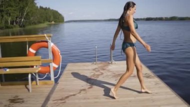 Ahşap iskeleden göle atlayan kadın. Yaz günü eğleniyorum. Rıhtımdan suya atlayan genç kız.