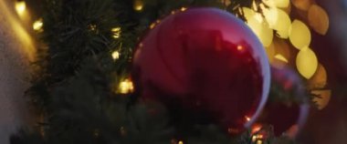 Süslü bir ağaca asılı kırmızı bir Noel topuna yaklaş. Yavaş çekim, yüzeysel alan derinliği. 