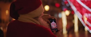 Noel Baba, şehrin sokaklarındaki Noel süslerinin fotoğrafını çekiyor. Yakın çekim, yavaş çekim, sığ odak. 