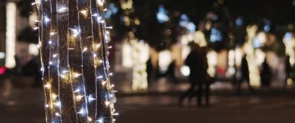 靠近一棵装饰着圣诞花环的树 旁边是过路的人 慢动作 浅焦点 — 图库视频影像