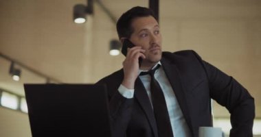 Ofiste çalışırken resmi takım elbiseli bir adam telefonda konuşuyor. Orta çekim, yavaş çekim..