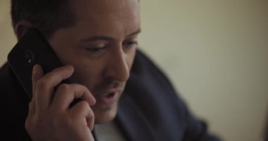 Yetişkin bir iş adamının takım elbiseli bir şekilde telefonla konuşmasını. Yavaş çekim.