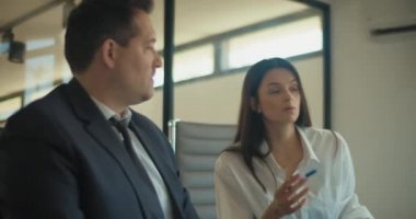 Takım elbiseli kadın ve erkek, toplantı odasında iş ortaklarıyla bir proje hakkında konuşuyorlar. Yavaş çekim.