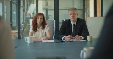 İki iş adamının ofis odasında iş arkadaşlarıyla buluştuğu orta ölçekli bir fotoğraf. Yavaş çekim.