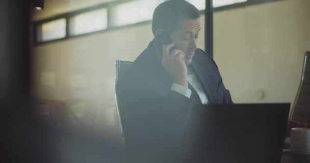 オフィスで働いている間 電話で真剣にストレスの多い会話をしているビジネスマン ガラスのドアの後ろの会議室の眺め スローモーション — ストック動画