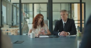 İki iş adamı iş arkadaşlarıyla toplantı odasında proje stratejisi hakkında konuşuyor. Orta çekim, yavaş çekim..