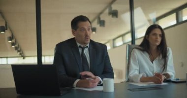 Takım elbiseli iki kişi iş projesi stratejisini iş arkadaşlarıyla toplantı odasında tartışıyor. Orta çekim, yavaş çekim..