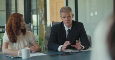 Bir iş görüşmesi sırasında, fikirlerini ekibin geri kalanıyla paylaşan iki kişinin orta boy fotoğrafı. Yavaş çekim.