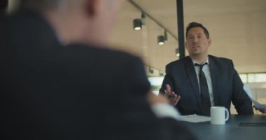 Ofisteki bir iş toplantısında pazarlama stratejisini tartışan iki işadamı. Orta çekim, yavaş çekim..