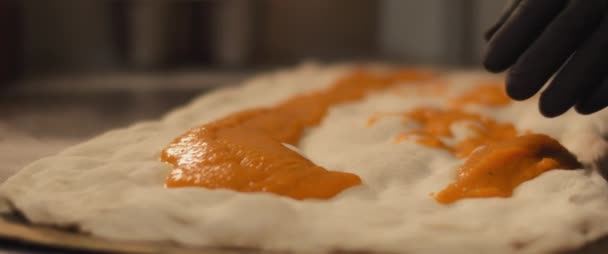 Chef extendiendo salsa de calabaza especial sobre una pizza fresca al taglio masa. Primer plano, cámara lenta. — Vídeo de stock