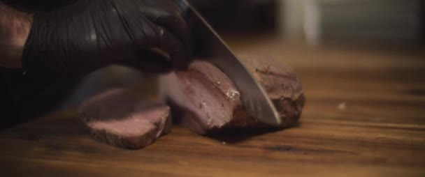 Bucătar în mănuși felii miza medie de carne rară cu cuțit. Închide, încetineşte mişcarea . — Videoclip de stoc