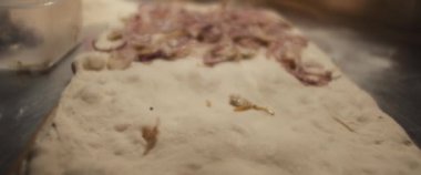 Kızarmış soğan pizza hamurunun üzerine yayılıyor, sinematik yakın çekim..