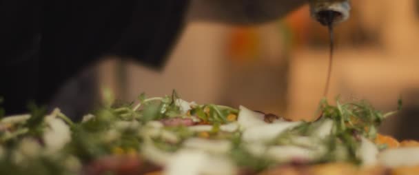 Chef italiano extendiendo salsa balsámica sobre una pizza tradicional al taglio con ingredientes. En cámara lenta, de cerca. — Vídeo de stock