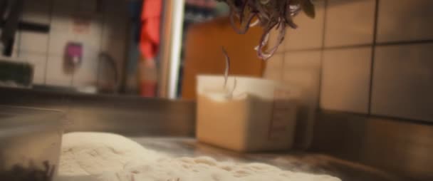 Chef strooit gebakken uien over een vers pizzadeeg, slow motion, lage hoek — Stockvideo