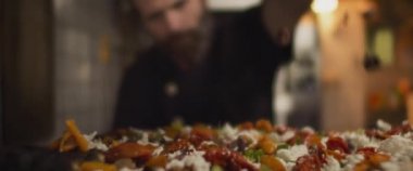 İtalyan şef geleneksel al taglio pizzasının üzerine sos serpiyor, yavaş çekim, sığ alan derinliği