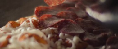 Geleneksel al taglio pizzasına peynirin üzerine pepperoni katmanı koyan bir şefin kapağı..