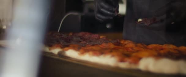 Chef colocando pepperoni encima de una pizza tradicional al taglio. Movimiento lento. — Vídeos de Stock