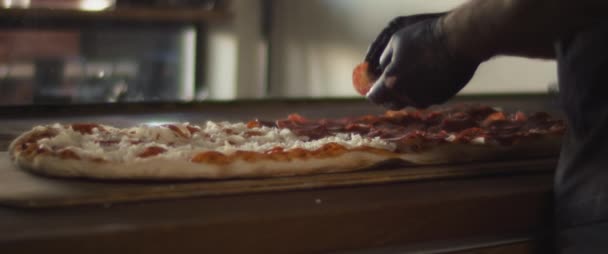 Итальянский шеф-повар кладет пепперони поверх сыра на традиционную пиццу Аль Тальо. — стоковое видео