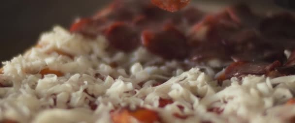 Gros plan d'un chef plaçant une couche de pepperoni sur du fromage sur une pizza traditionnelle al taglio. — Video