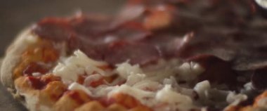 Geleneksel al taglio pizzasına peynirin üzerine pepperoni katmanı koyan bir şefin kapağı..