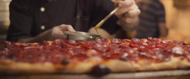 Chef italien étalant l'huile d'olive avec un pinceau sur la pizza pepperoni al taglio traditionnelle. Gros plan — Video