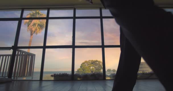穿着西装的男人在日落时走向大窗户 看着湖面 检查他的手机 慢动作 宽镜头 玩具娃娃 — 图库视频影像
