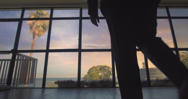 Mann Anzug Geht Bei Sonnenuntergang Auf Das Große Fenster Schaut — Stockvideo