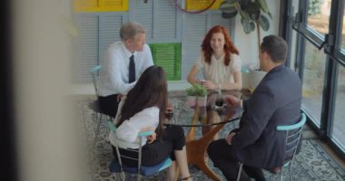 Kahve molası sırasında konuşan ve gülen dört yaratıcı insandan oluşan bir iş ekibi. Yavaş çekim.