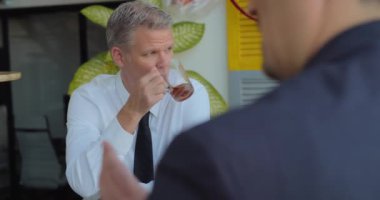 İş adamı çay içiyor ve öğle arasında iş arkadaşlarıyla konuşuyor. Yavaş çekim, orta çekim..