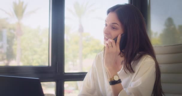 Ofiste Dizüstü Bilgisayarla Çalışırken Telefonda Gülümseyen Bir Kadını Ortalama Çekim — Stok video