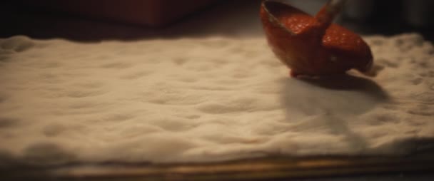 Tomatensauce, die auf einem frischen Pizzateig verteilt wird. Nahaufnahme, Zeitlupe. — Stockvideo