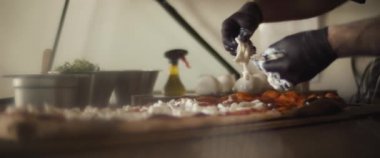 Geleneksel al taglio pizzasının üzerine burrata peyniri serpiştiren bir şefe yaklaş..